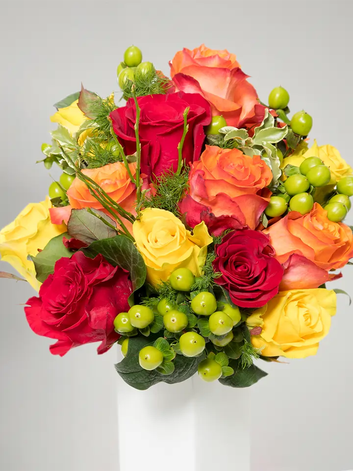 Bouquet di rose aranco rosse giallo e bacche verdi close up